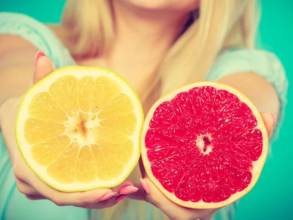 Helften van gele rode grapefruit citrusvruchten in menselijke handen — Stockfoto