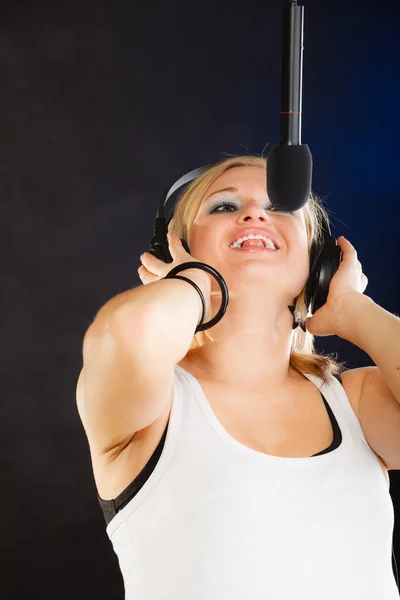 对在播音室里戴着耳机的麦克风唱歌的女人 — 图库照片