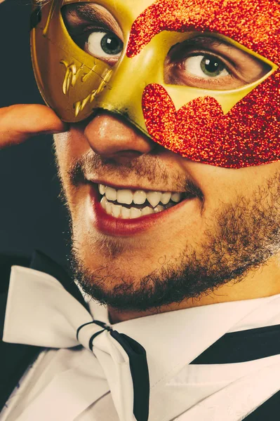 Junger Mann mit Karnevalsmaske auf dunklem Untergrund — Stockfoto