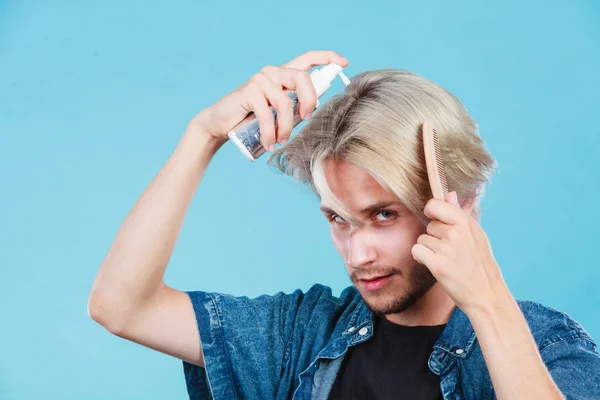 Man applying spray cosmetic to his hair