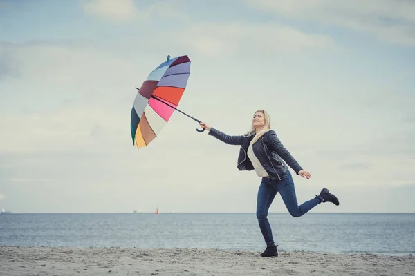 Mujer saltando con paraguas de colores en la playa — Foto de Stock