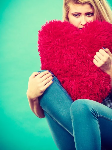 Mujer triste sosteniendo almohada roja en forma de corazón —  Fotos de Stock