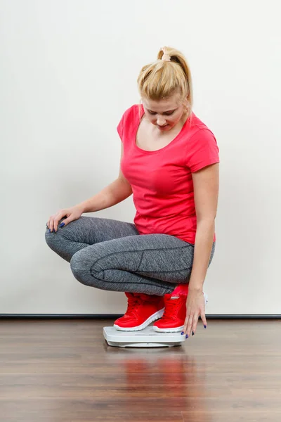 Woman wearing sportswear standing on weight machine — Stock Photo, Image