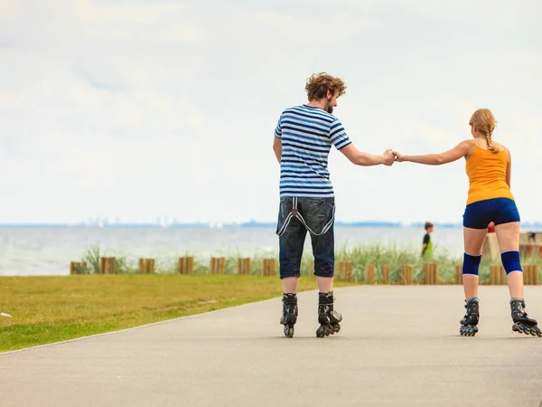 Pareja joven en patines de ruedas montando al aire libre —  Fotos de Stock