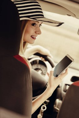 Arabasını kullanırken telefonu kullanan bir kadın.