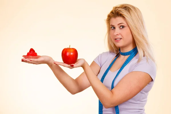 Woman with measuring tape choosing what to eat — Stock Photo, Image