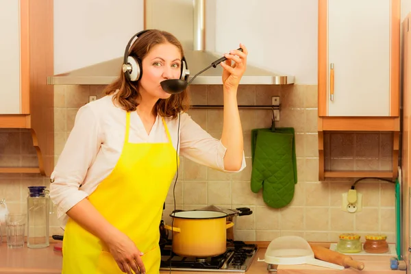 Dona de casa com fones de ouvido na cozinha — Fotografia de Stock