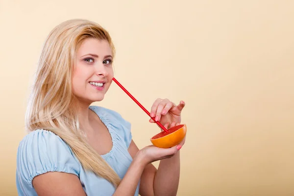 Женщина пьет сок из фруктов, красный грейпфрут — стоковое фото