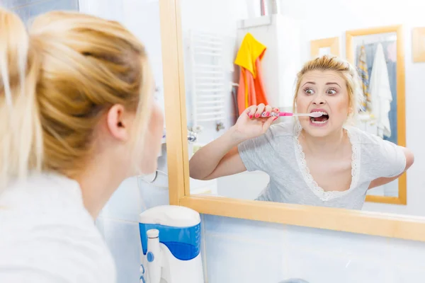 Mulher escovando os dentes de limpeza no banheiro — Fotografia de Stock