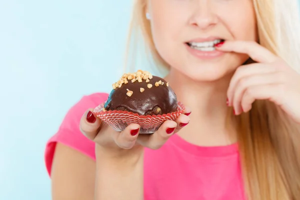 Жінка тримає шоколадний кекс збирається вкусити — стокове фото
