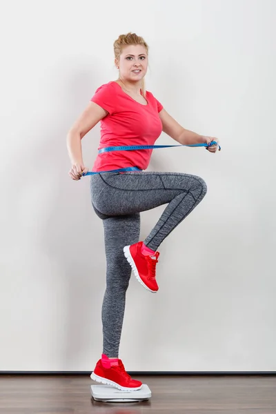 Woman wearing sportswear standing on weight machine — Stock Photo, Image