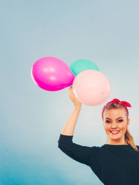 Tatlı gülümseyen kız renkli balonlar tutar.