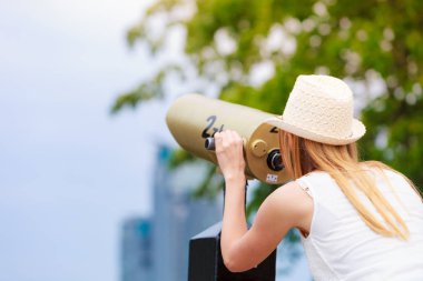 Teleskopla bakarak güneş şapkalı kadın turist