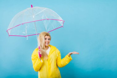 Hava kontrol şemsiye tutan yağmurluk giyen kadın