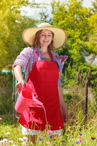 Mujer regando flores en el jardín — Foto de Stock