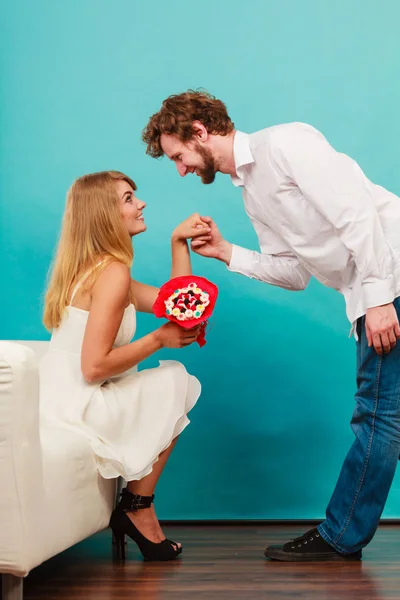 Uomo dando donna caramelle mazzo di fiori. Coppia felice — Foto Stock