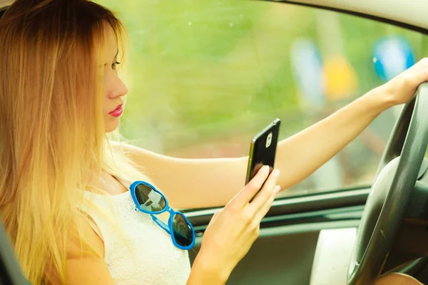 Mujer usando el teléfono mientras conduce su coche — Foto de Stock