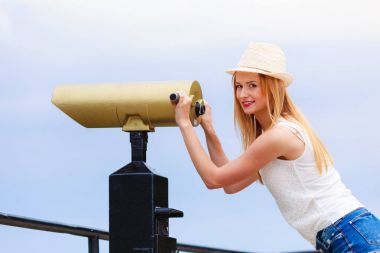 Teleskopla bakarak güneş şapkalı kadın turist