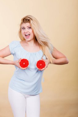 Kırmızı greyfurt meme üzerinde tutan kadın