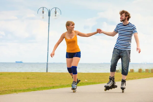 Pareja joven en patines de ruedas montando al aire libre — Foto de Stock