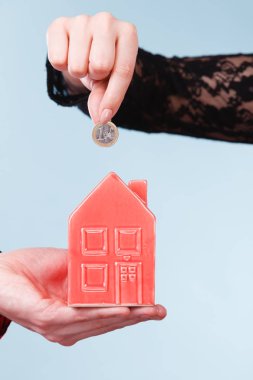 İnsanlar elleriyle küçük ev ve gümüş sikke.