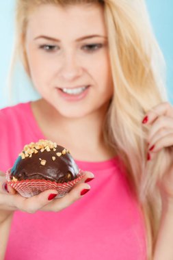 Çikolatalı kek tutan kadın ısırmak üzere.