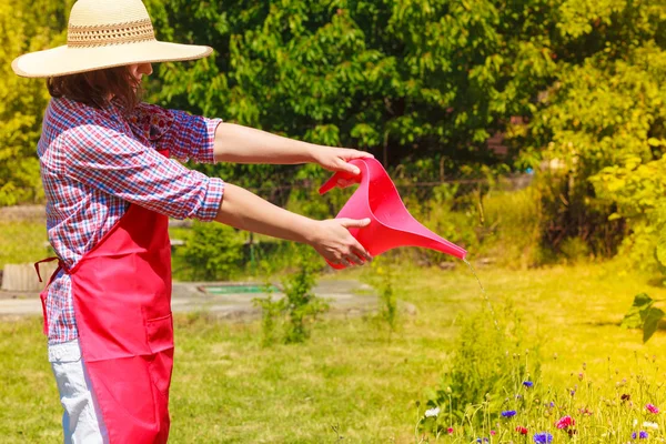 Жінка поливає рослини в саду — стокове фото