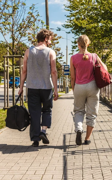Couple man and woman walking with sport bags.