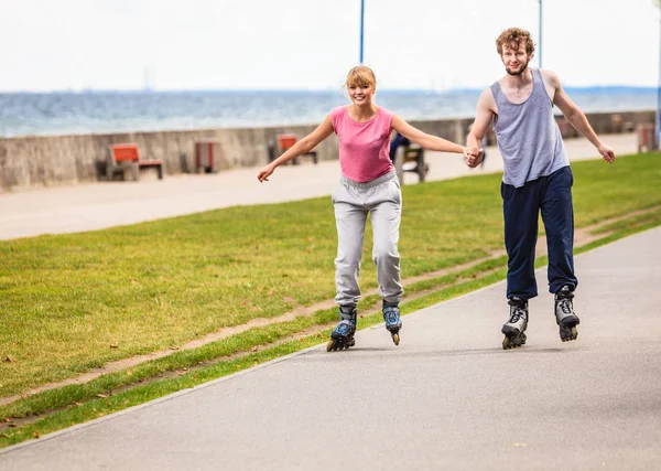 Pareja joven patinando en parque tomados de la mano . — Foto de Stock