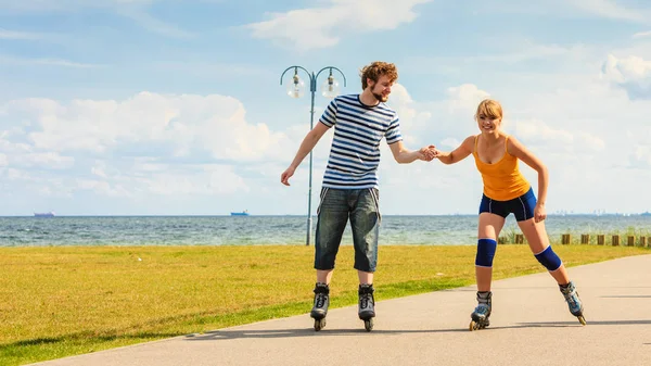 Jovem casal em patins andando ao ar livre — Fotografia de Stock