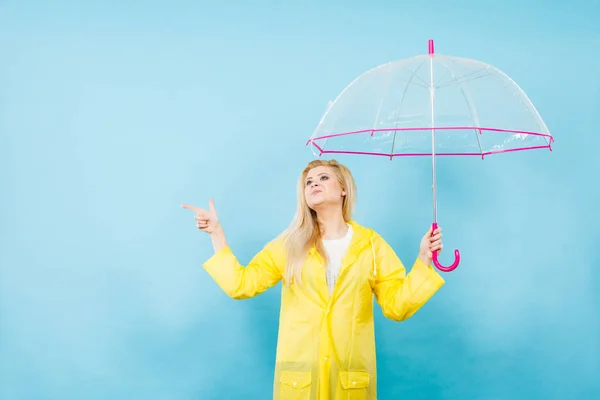 Mujer con impermeable sosteniendo paraguas apuntando — Foto de Stock