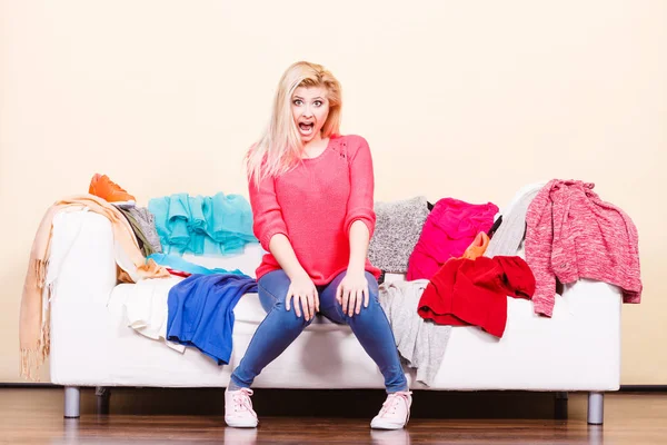 Woman does not know what to wear sitting on couch — Stock Photo, Image