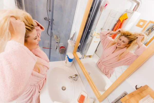 Mujer mirando su cabello rubio muy enredado — Foto de Stock