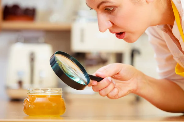 Mujer inspeccionando miel con lupa . — Foto de Stock