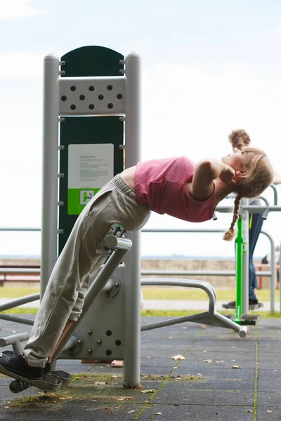 Actieve vrouw uitoefenen op backtrainer buiten. — Stockfoto