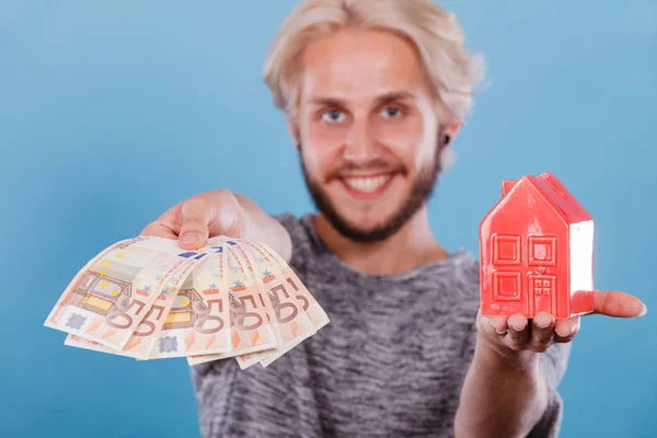 Man holds money and house piggybank