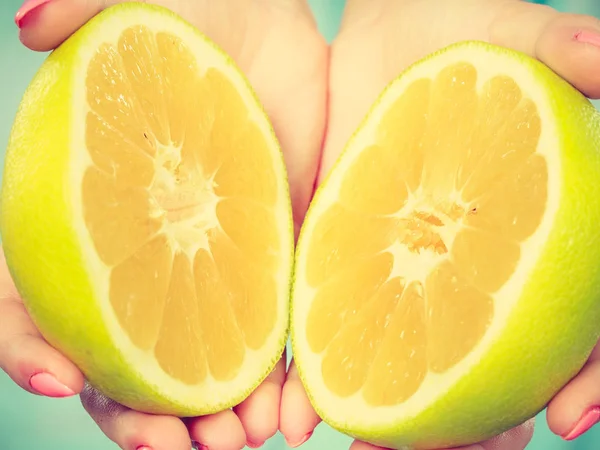 Helften van gele grapefruit citrusvruchten in menselijke handen — Stockfoto