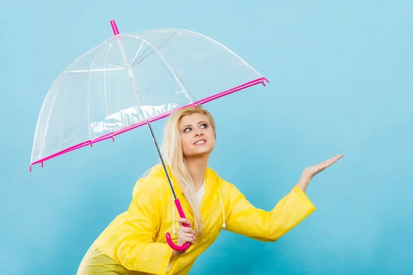 Kvinna som bär regnrock innehar paraply kontrollera väder — Stockfoto