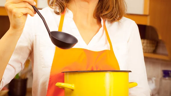 Mulher com concha e panela na cozinha — Fotografia de Stock