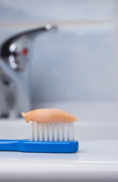 Escova de dentes azul com pasta no banheiro na pia — Fotografia de Stock