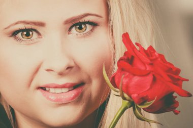 Kırmızı gül yakınındaki yüz tutan Closeup kadın.