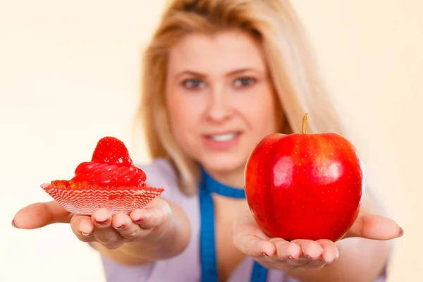 Woman choosing between apple and sweet cupcake — Stock Photo, Image