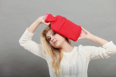 Kırmızı sıcak su şişesi üzerinde kafa tutan kadın