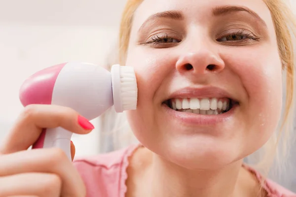 Счастливая женщина с помощью щетки для чистки лица — стоковое фото