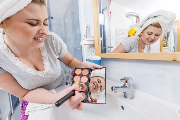 Женщина в ванной комнате наносит контурный бронзатор на кисть — стоковое фото