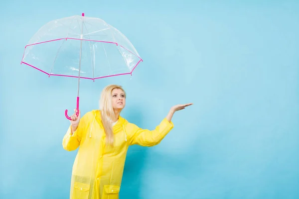 Mujer vistiendo impermeable sosteniendo paraguas comprobando el clima — Foto de Stock