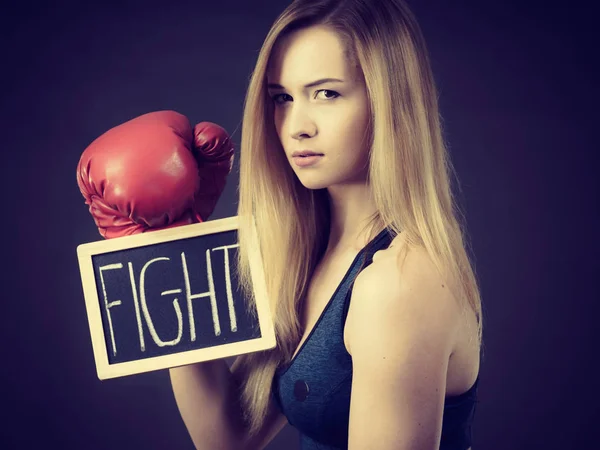 Mujer usando guante de boxeo sosteniendo signo de lucha — Foto de Stock