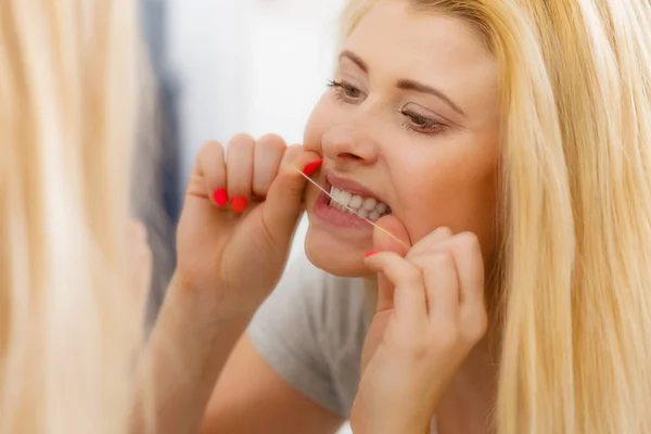 Mulher limpando os dentes usando fio dental — Fotografia de Stock