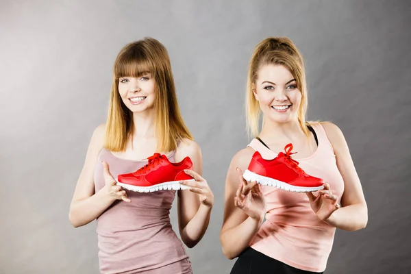 Dos mujeres presentando zapatillas deportivas zapatillas —  Fotos de Stock