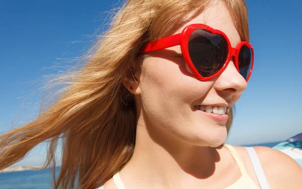 Menina em óculos de sol vermelhos relaxante na costa do mar . — Fotografia de Stock